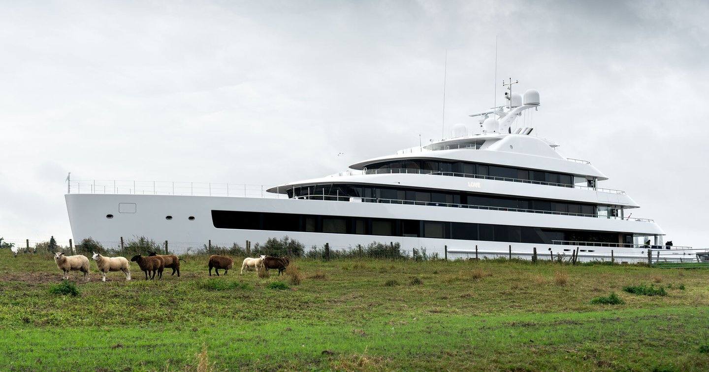 The Feadship superyacht Love passing a field with sheep during her Dutch waterway transit